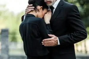 A couple hugging while they mourn the death of a loved one who died at the fault of another. They are contemplating contacting an Austin wrongful death attorney.