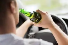 A man drinking a beer while driving who is going to need an Austin drunk driving accident attorney soon.
