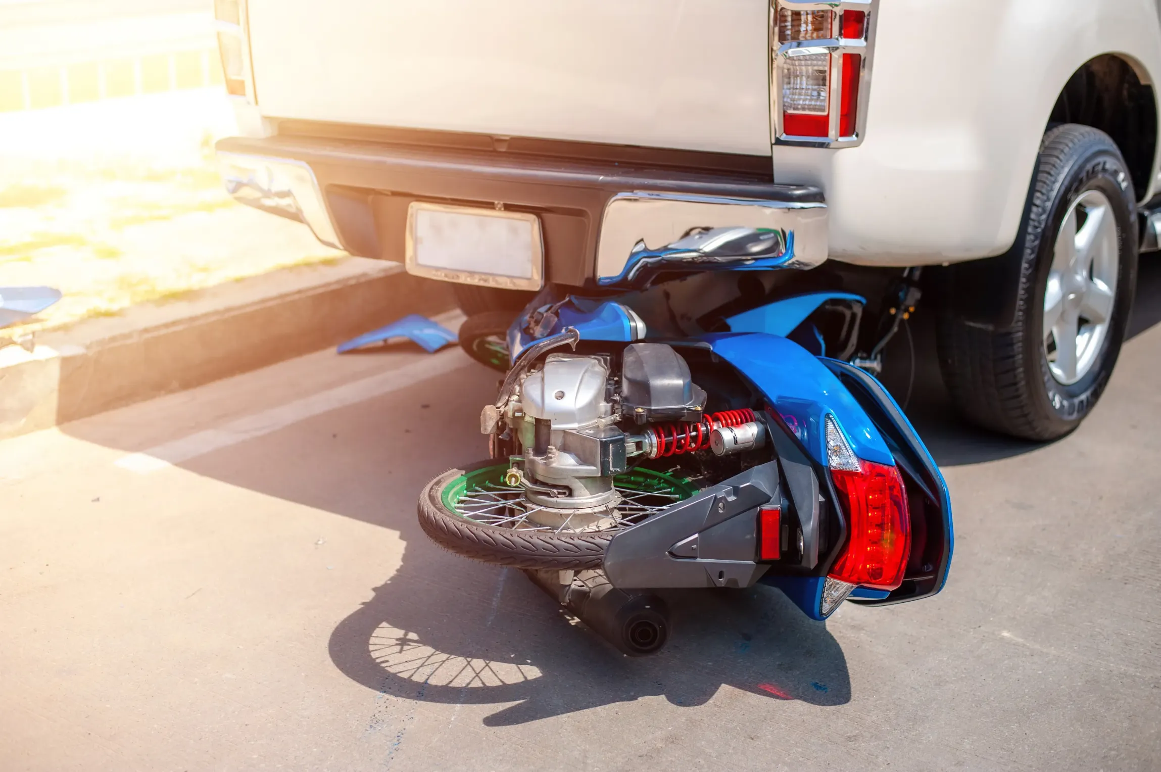A motorcycle wrecked under a pick up truck.