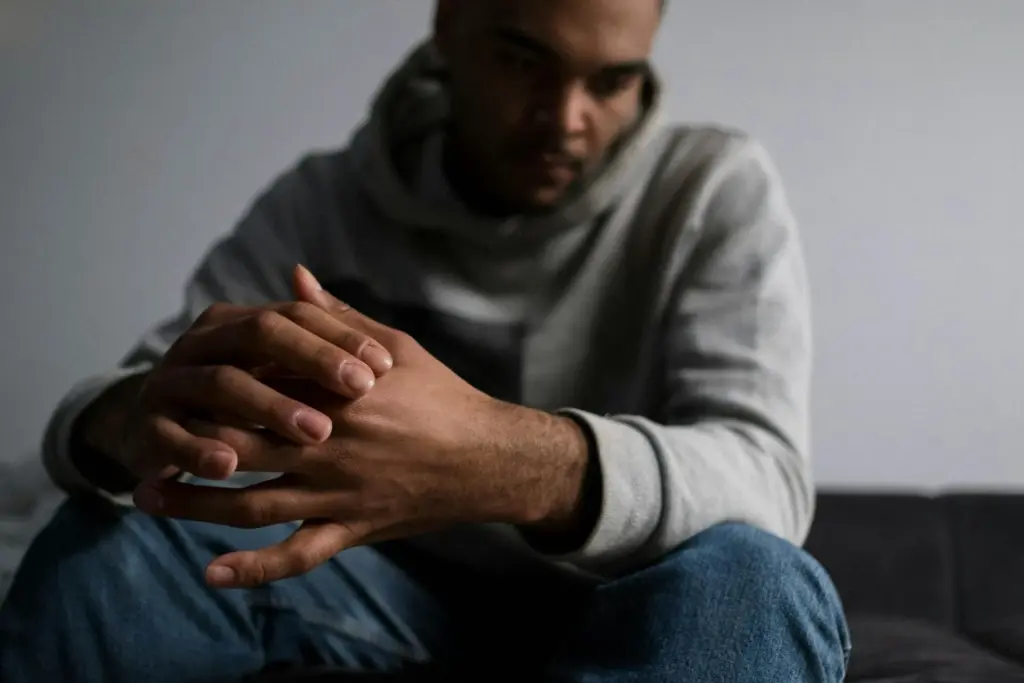 A man that is stressed, sitting on a couch.