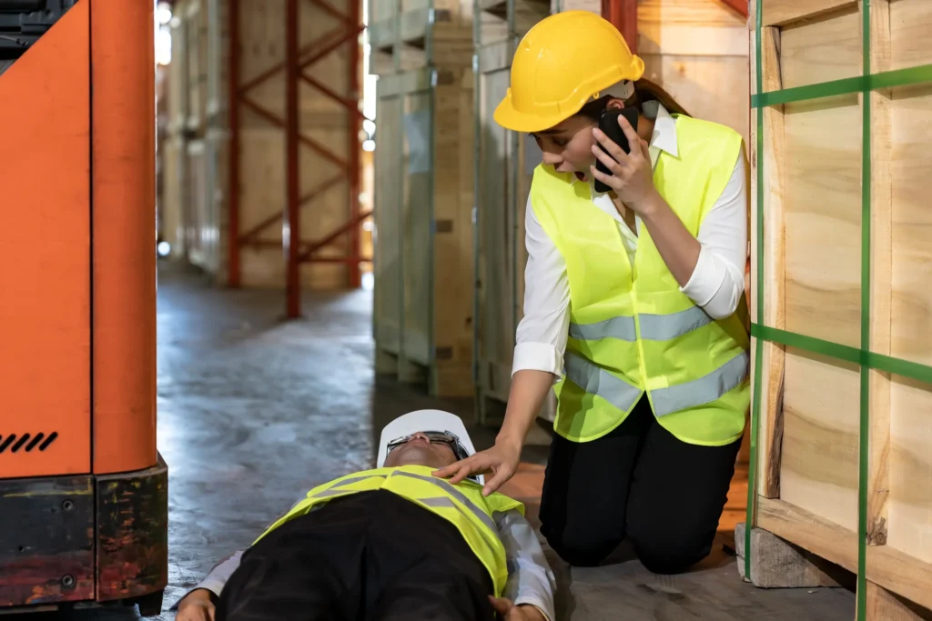 Warehouse worker feeling for an injured coworker's pulse.