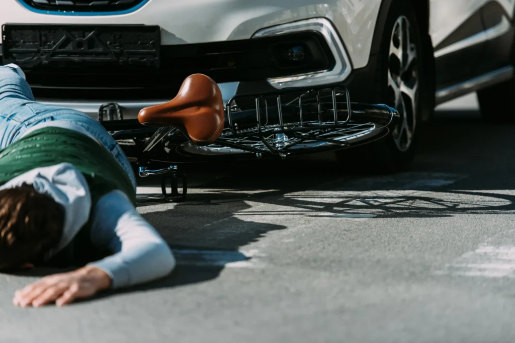 A man on a bicycle after being hit by a car.