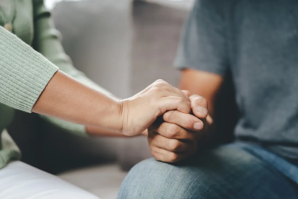 A woman holding a man's hands for comfort.