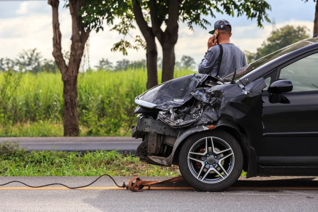 A man standing by his car after a hit and run accident.